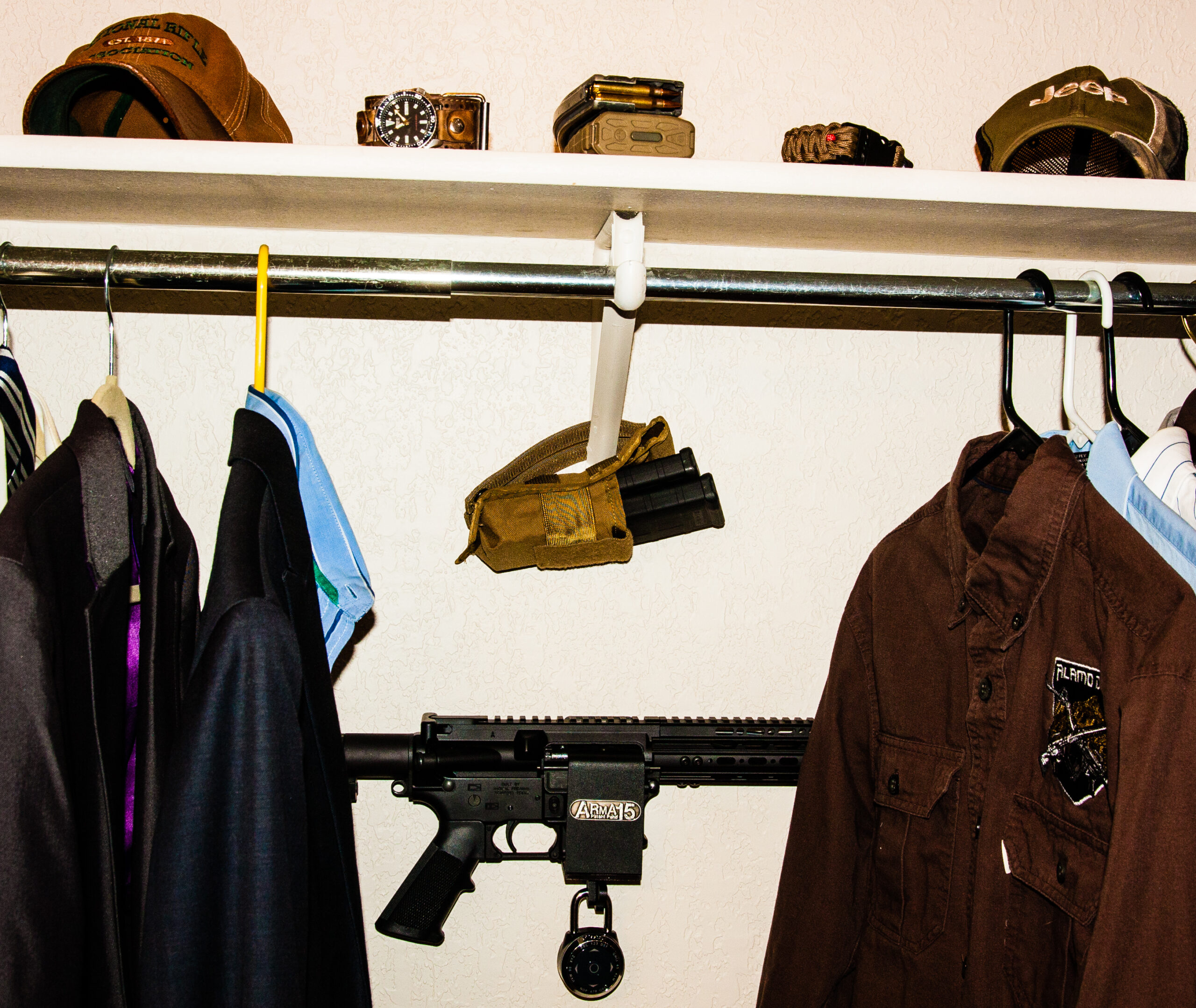 AR15 secured horizontally in an ARmA15 wall mount inside a closet behind hanging clothes.